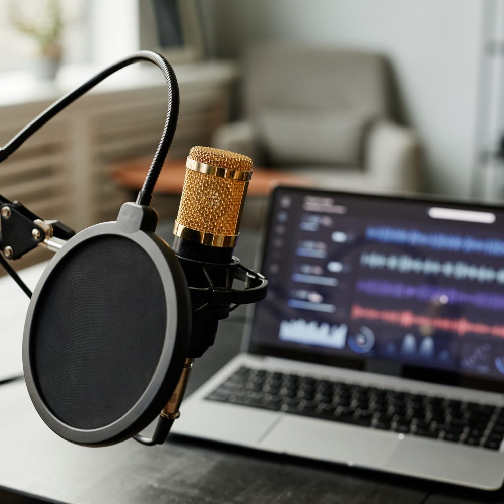 Close up background image of recording studio with microphone and audio tracks on laptop screen, copy space